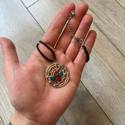 Spider-Man 2006 Web Silver Necklace is a necklace with a black cord and a circular silver-tone metal pendant. The front features a web background with a colored Spider-Man figure in a swinging pose, while the back is plain metal with 2006 licensing.