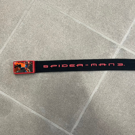 Spider-Man 3 2007 Black Belt is a black adjustable belt featuring repeated horizontal red Spider-Man 3 logo graphics across the strap. The belt has a red metal buckle with a Spider-Man graphic on the front showing him swinging. It includes a metal belt tip finish and a regulated sizing system for adjustment.
