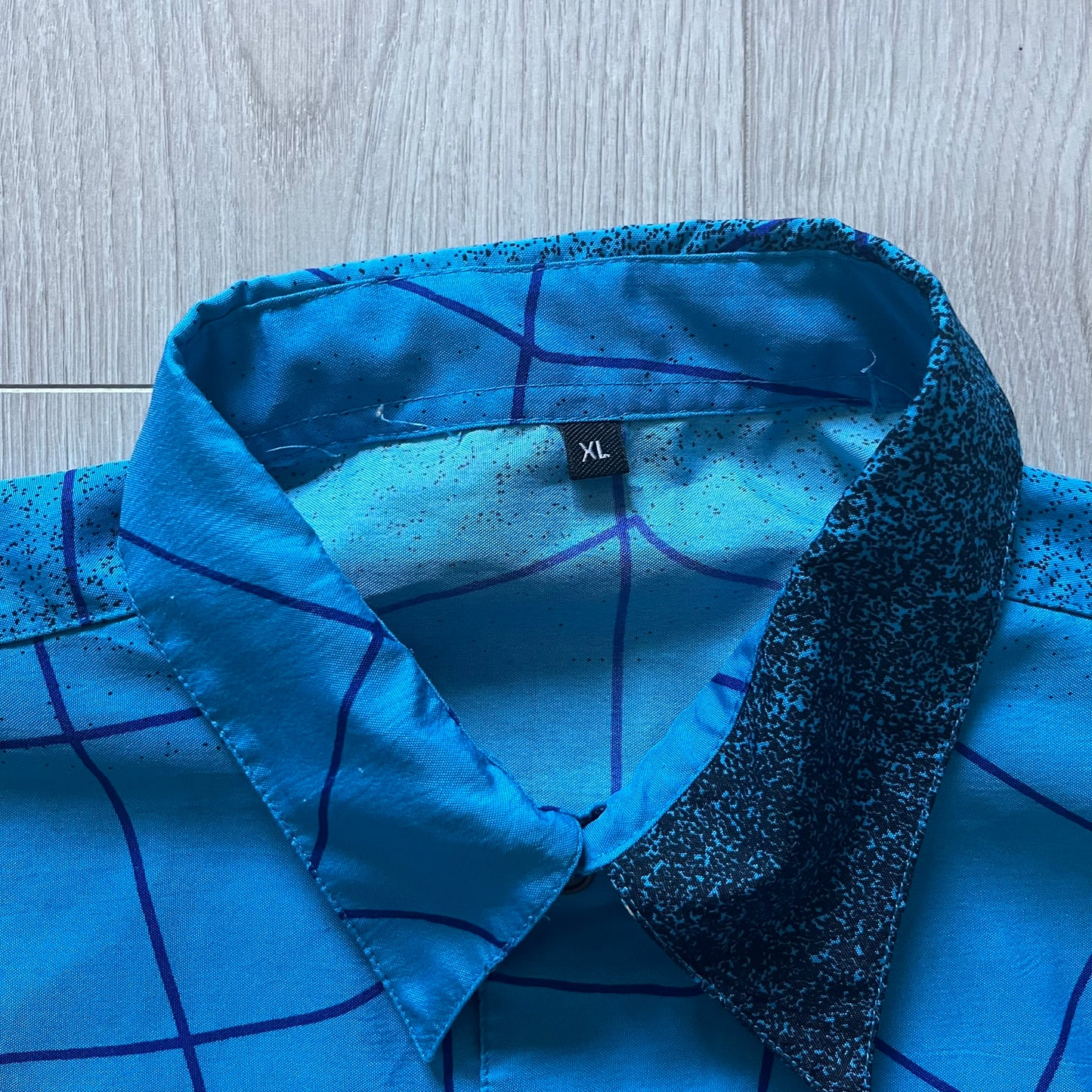 Blue Spider-Man button-up shirt featuring an all-over web print and mirrored graphics of Spider-Man shooting webs on both sides. Centered Spider-Man logo completes the great design. A striking, comic-inspired piece perfect for fans and collectors.