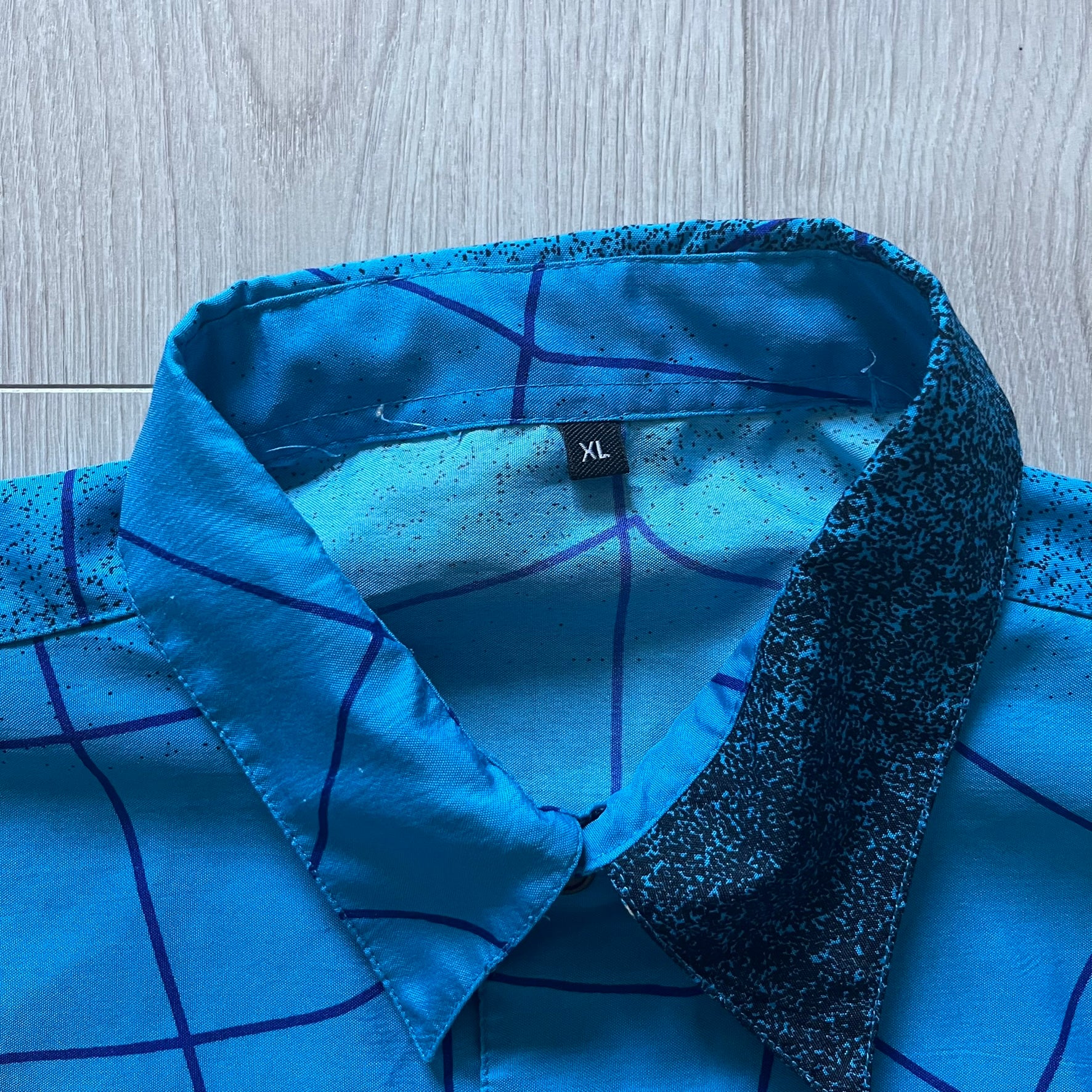 Blue Spider-Man button-up shirt featuring an all-over web print and mirrored graphics of Spider-Man shooting webs on both sides. Centered Spider-Man logo completes the great design. A striking, comic-inspired piece perfect for fans and collectors.