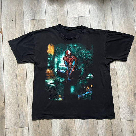 Spider-Man Marvel Timestorm 2009–2099 Tee is a black T-shirt featuring the Timestorm 2009–2099 cover graphic. The print shows Spider-Man half in his classic design and half in the 2099 version, sitting with a blurred green city background. Made by Marvel Mad Engine, the shirt highlights the multiversal crossover design.