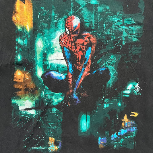 Spider-Man Marvel Timestorm 2009–2099 Tee is a black T-shirt featuring the Timestorm 2009–2099 cover graphic. The print shows Spider-Man half in his classic design and half in the 2099 version, sitting with a blurred green city background. Made by Marvel Mad Engine, the shirt highlights the multiversal crossover design.