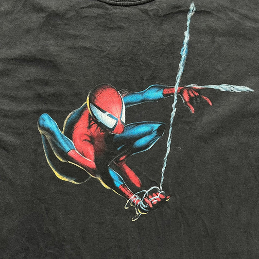 Spider-Man Swinging 2003 Washed Longsleeve is a washed black and dark gray cotton long-sleeve shirt made on a Hanes Beefy-T blank. The front features a large detailed comic-style Spider-Man graphic in red and blue, showing the character swinging in motion. Made from 100% cotton with a faded vintage finish.
