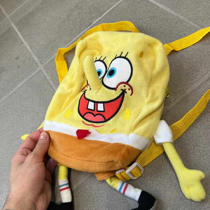 SpongeBob SquarePants 2010 Backpack is designed in the shape of SpongeBob’s body with embroidered facial details, a 3D nose, and loose hanging arms and legs. It features one main compartment and a yellow 2010 licensed tag on the side.
