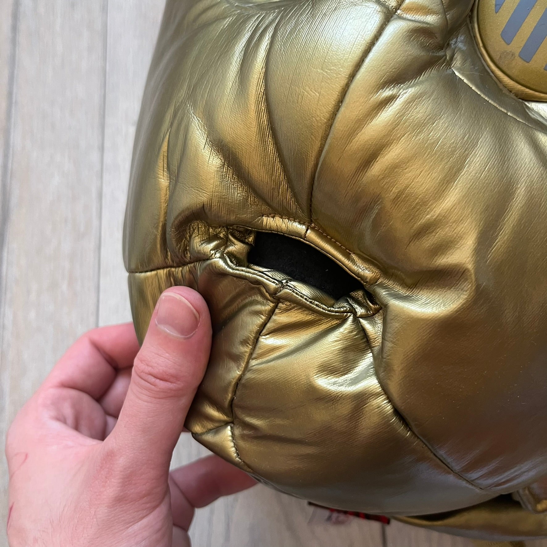 Star Wars 1990s C-3PO Head Backpack is a novelty backpack shaped like the head of C-3PO. It features a metallic gold finish with detailed sculpted paneling and plastic lens-style eyes for a robotic look. The bag includes a 1990s Star Wars red licensed tag and a single main compartment.