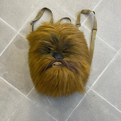  Star Wars 1990s Chewbacca Head Backpack is a novelty bag designed in the shape of Chewbacca’s head. The exterior features a furry construction with plastic eyes and a leather-like nose and mouth. It includes an adjustable shoulder straps, a single main compartment and a red Star Wars licensed tag.