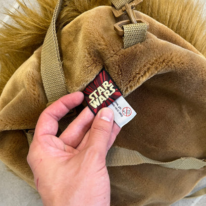  Star Wars 1990s Chewbacca Head Backpack is a novelty bag designed in the shape of Chewbacca’s head. The exterior features a furry construction with plastic eyes and a leather-like nose and mouth. It includes an adjustable shoulder straps, a single main compartment and a red Star Wars licensed tag.