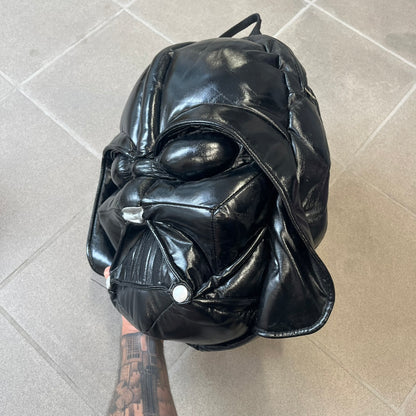 Star Wars 1990s Darth Vader Head Backpack is a vintage backpack shaped like Darth Vader’s helmet. It is finished in shiny black with molded plastic details recreating the character’s mask and helmet. The bag has one main compartment and includes a red Star Wars licensed tag from the 1990s.