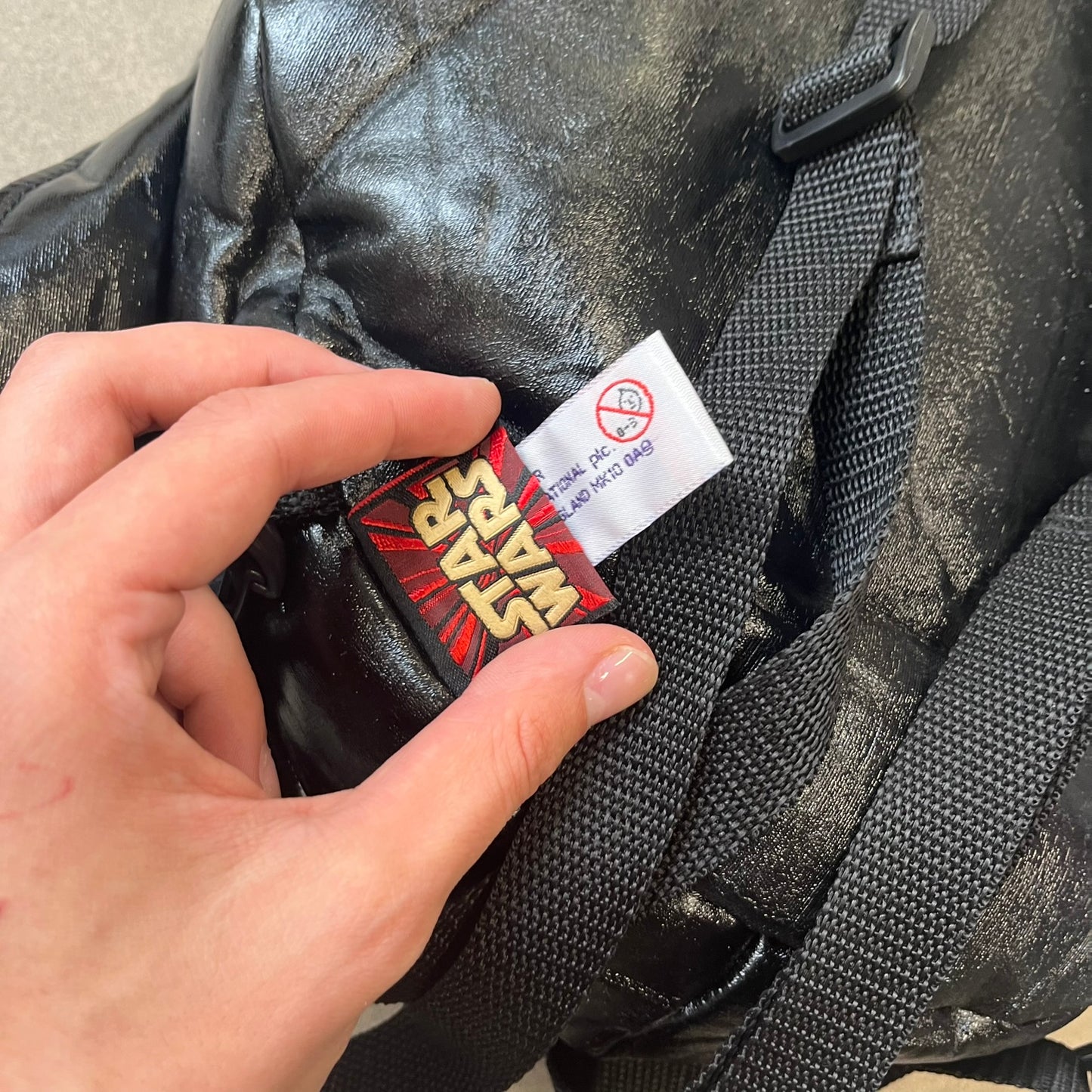 Star Wars 1990s Darth Vader Head Backpack is a vintage backpack shaped like Darth Vader’s helmet. It is finished in shiny black with molded plastic details recreating the character’s mask and helmet. The bag has one main compartment and includes a red Star Wars licensed tag from the 1990s.