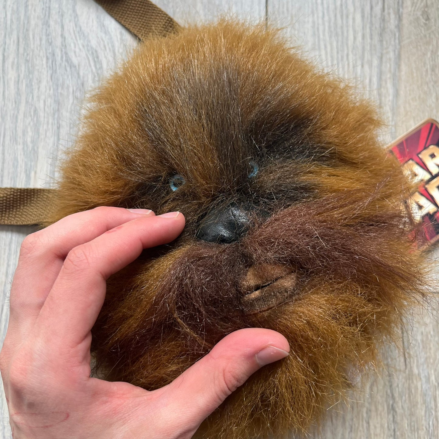 Star Wars 1990s Chewbacca Head Shoulder Bag is a novelty shoulder bag designed in the shape of Chewbacca’s head. The exterior features a furry construction with plastic eyes and a leather-like nose and mouth. It includes an adjustable shoulder strap, a single main compartment, a red Star Wars licensed tag, and the original paper tag.