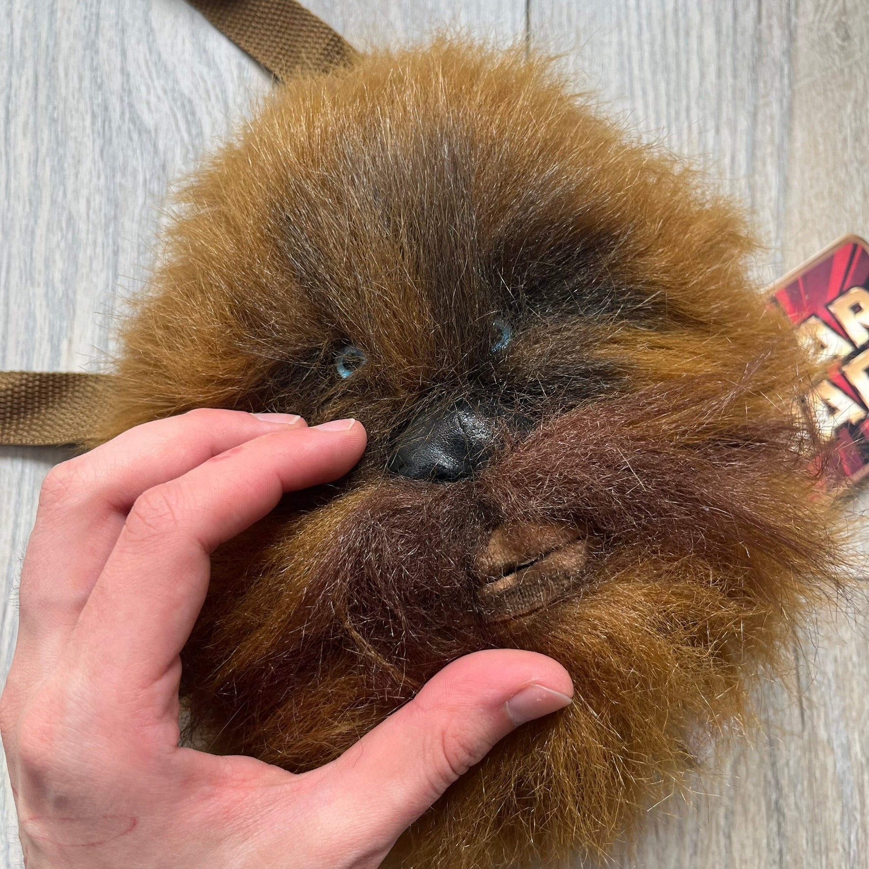 Star Wars 1990s Chewbacca Head Shoulder Bag is a novelty shoulder bag designed in the shape of Chewbacca’s head. The exterior features a furry construction with plastic eyes and a leather-like nose and mouth. It includes an adjustable shoulder strap, a single main compartment, a red Star Wars licensed tag, and the original paper tag.
