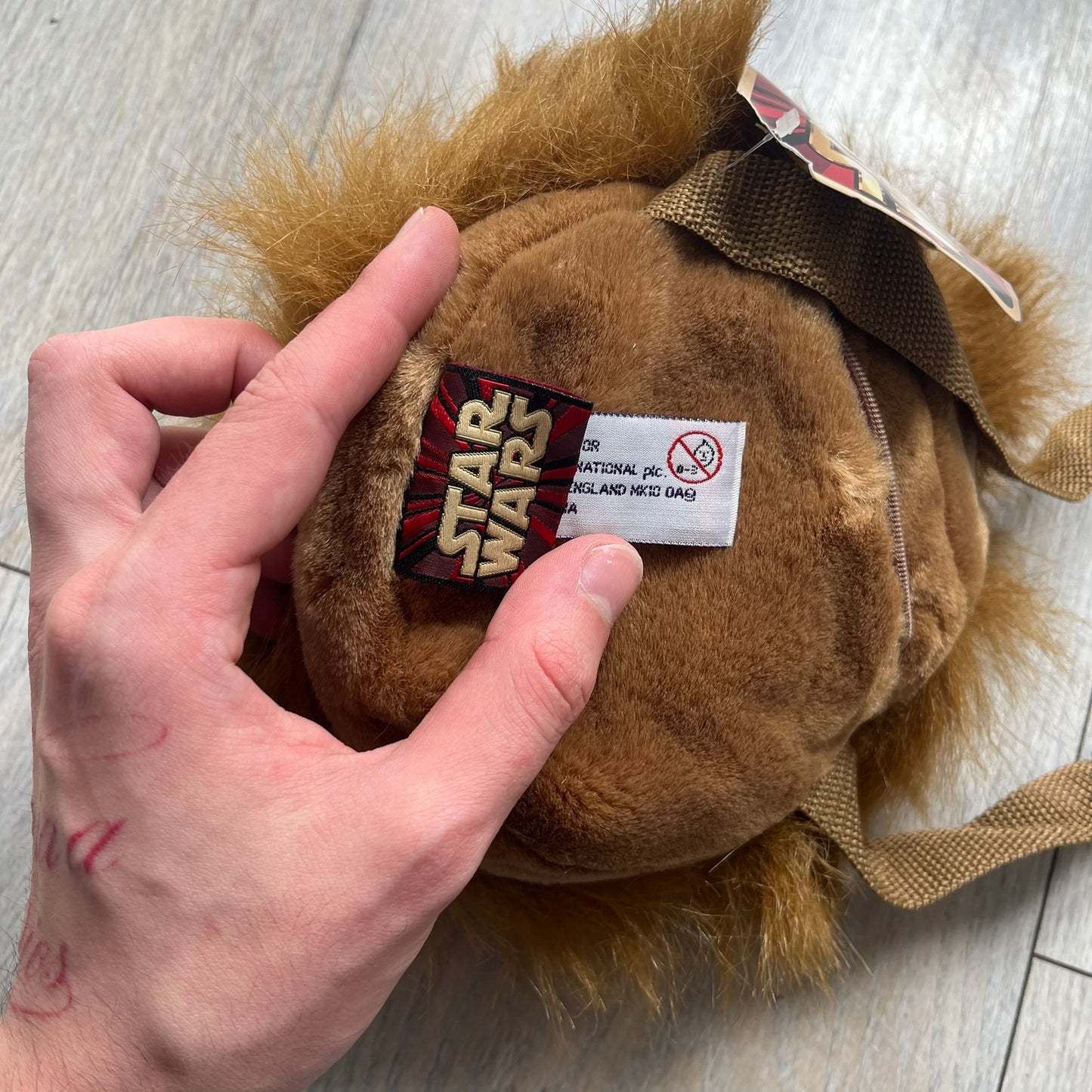 Star Wars 1990s Chewbacca Head Shoulder Bag is a novelty shoulder bag designed in the shape of Chewbacca’s head. The exterior features a furry construction with plastic eyes and a leather-like nose and mouth. It includes an adjustable shoulder strap, a single main compartment, a red Star Wars licensed tag, and the original paper tag.