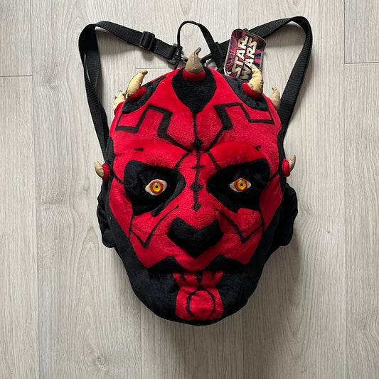 Star Wars 90's Darth Maul Head Backpack - a plush backpack shaped like Darth Maul’s head with striking red-and-black detailing and realistic plastic eyes. Features a small zip compartment on the back and adjustable straps, perfect as a collectible or standout accessory.