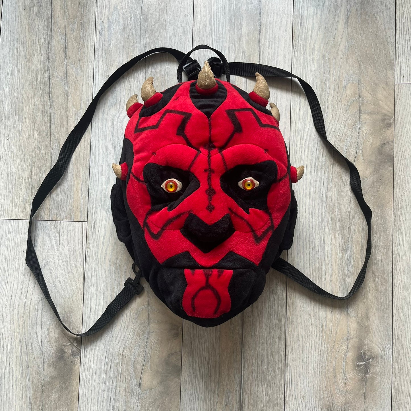 Star Wars 90's Darth Maul Head Backpack is a plush backpack shaped like Darth Maul’s head with striking red-and-black detailing and realistic plastic eyes. Features a small zip compartment on the back and adjustable straps, perfect as a collectible or standout accessory.