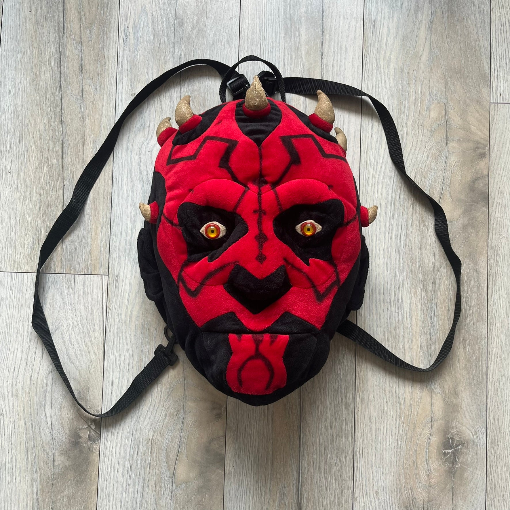 Star Wars 90's Darth Maul Head Backpack is a plush backpack shaped like Darth Maul’s head with striking red-and-black detailing and realistic plastic eyes. Features a small zip compartment on the back and adjustable straps, perfect as a collectible or standout accessory.