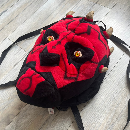 Star Wars 90's Darth Maul Head Backpack is a plush backpack shaped like Darth Maul’s head with striking red-and-black detailing and realistic plastic eyes. Features a small zip compartment on the back and adjustable straps, perfect as a collectible or standout accessory.