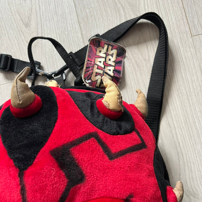 Star Wars 90's Darth Maul Head Backpack - a plush backpack shaped like Darth Maul’s head with striking red-and-black detailing and realistic plastic eyes. Features a small zip compartment on the back and adjustable straps, perfect as a collectible or standout accessory.