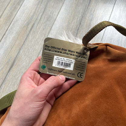 Star Wars 1990s Ewok Wicket Head Backpack is a plush backpack designed in the shape of the Ewok character Wicket W. Warrick. The bag features a brown Ewok face with a white beard and a brown hood, along with green camo-style shoulder straps. It includes a 1990s Star Wars neck tag and original paper tag.