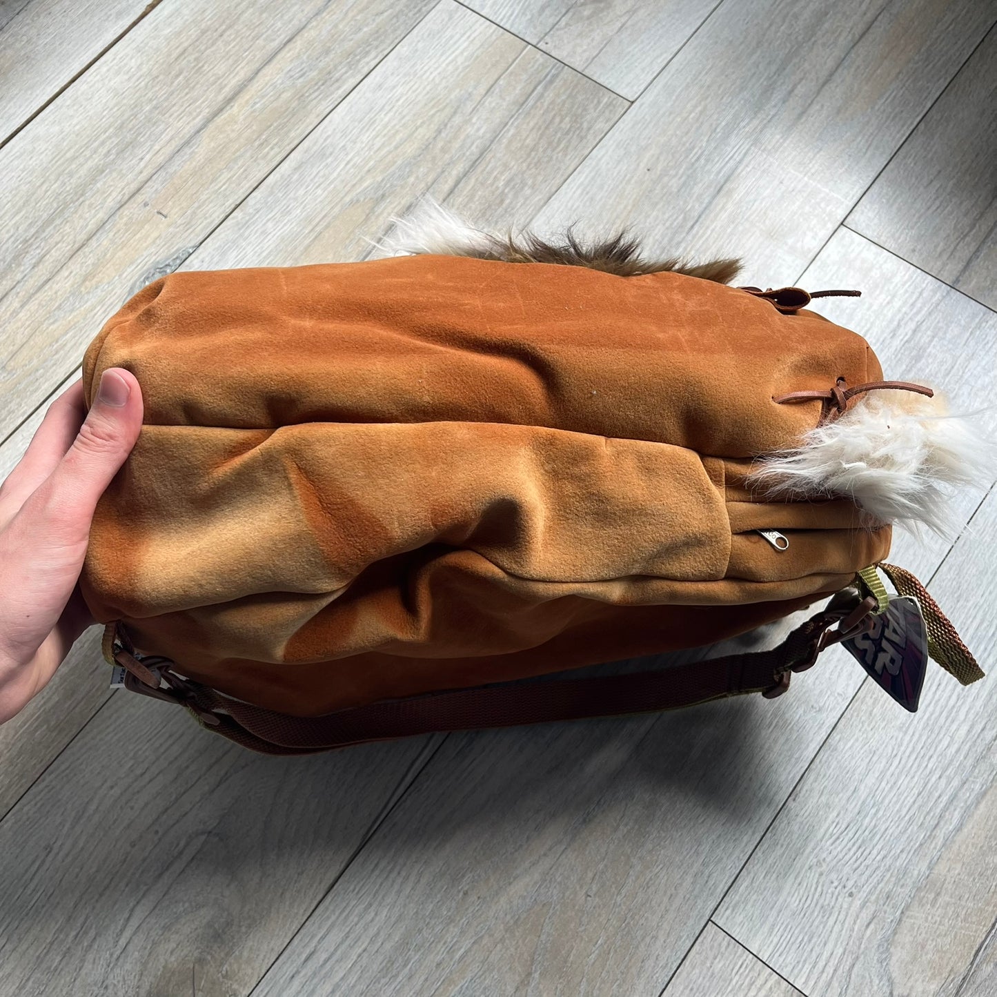 Star Wars 1990s Ewok Wicket Head Backpack is a plush backpack designed in the shape of the Ewok character Wicket W. Warrick. The bag features a brown Ewok face with a white beard and a brown hood, along with green camo-style shoulder straps. It includes a 1990s Star Wars neck tag and original paper tag.
