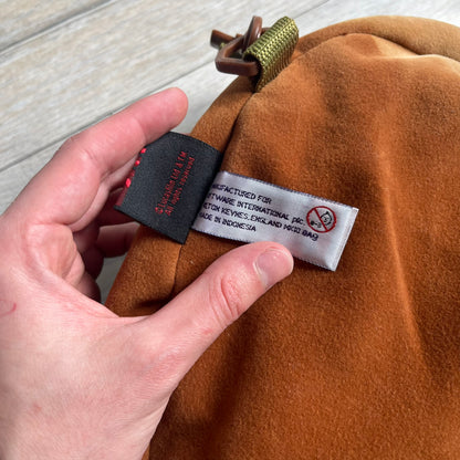 Star Wars 1990s Ewok Wicket Head Backpack is a plush backpack designed in the shape of the Ewok character Wicket W. Warrick. The bag features a brown Ewok face with a white beard and a brown hood, along with green camo-style shoulder straps. It includes a 1990s Star Wars neck tag and original paper tag.