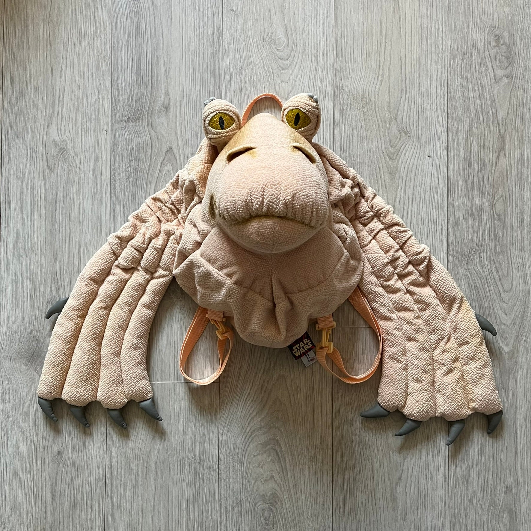 Vintage 1990s Star Wars backpack shaped like Jar Jar Binks’ head, complete with oversized ears for a playful, collectible design. This nostalgic piece captures the quirky charm of the character while offering functional storage. A rare, fun accessory for fans of classic Star Wars memorabilia.