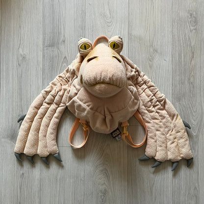Vintage 1990s Star Wars backpack shaped like Jar Jar Binks’ head, complete with oversized ears for a playful, collectible design. This nostalgic piece captures the quirky charm of the character while offering functional storage. A rare, fun accessory for fans of classic Star Wars memorabilia.