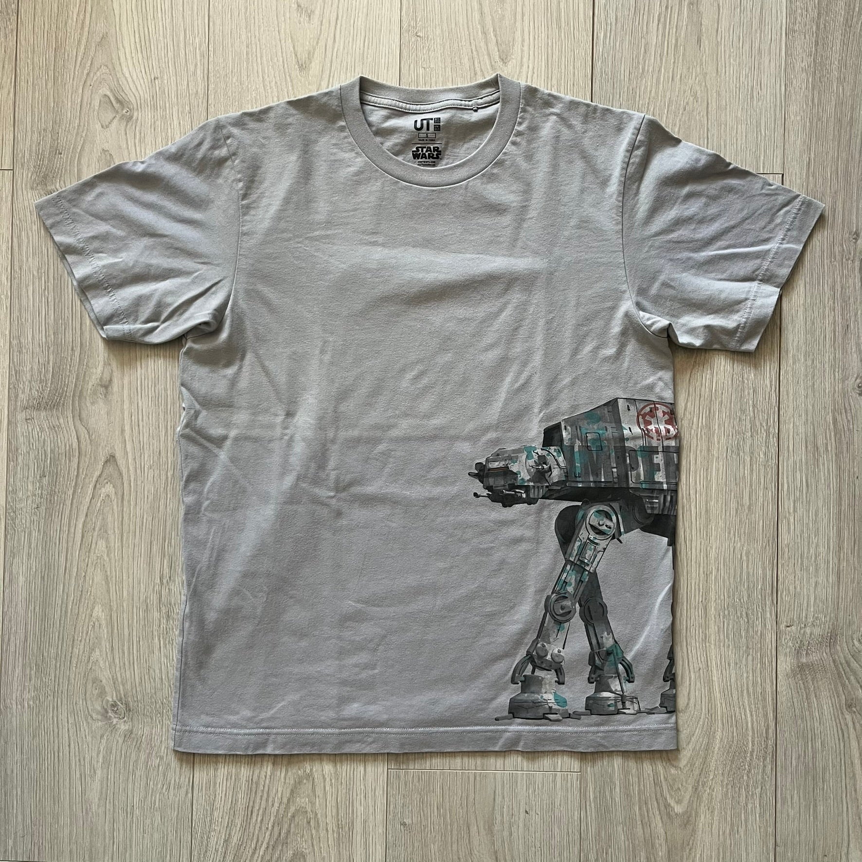 Gray t-shirt with a robot graphic on a wooden surface