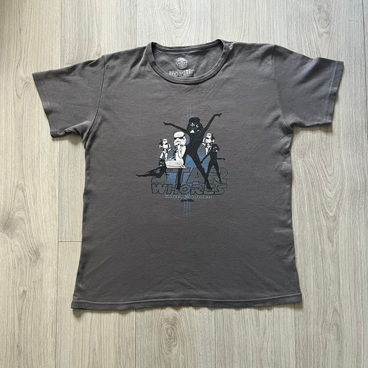 Gray Star Wh*res tee showcasing female figures in Stormtrooper and Vader masks. Logo sits prominently on the chest with witty “Available in Alderaan Places” tagline beneath. A perfect sci-fi parody tee.