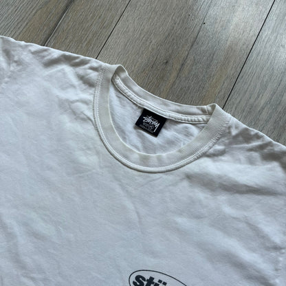 Stussy Soul 1980 White Tee is a white short-sleeve T-shirt released as part of a spring drop, made from soft cotton with a relaxed fit and ribbed collar. The front features a small Stussy logo print on the chest, while the back includes black Stussy text, a large multicolor central graphic, and “Copyright 1980” text at the bottom.
