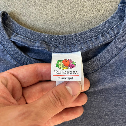 Subway Surfers 2010s Jake Tee is a grey T-shirt made on a Fruit of the Loom blank. The front features Jake, the main character from Subway Surfers, riding his skateboard, with the pursuing guard dog biting the end of the board. The design is printed in full color on the front.
