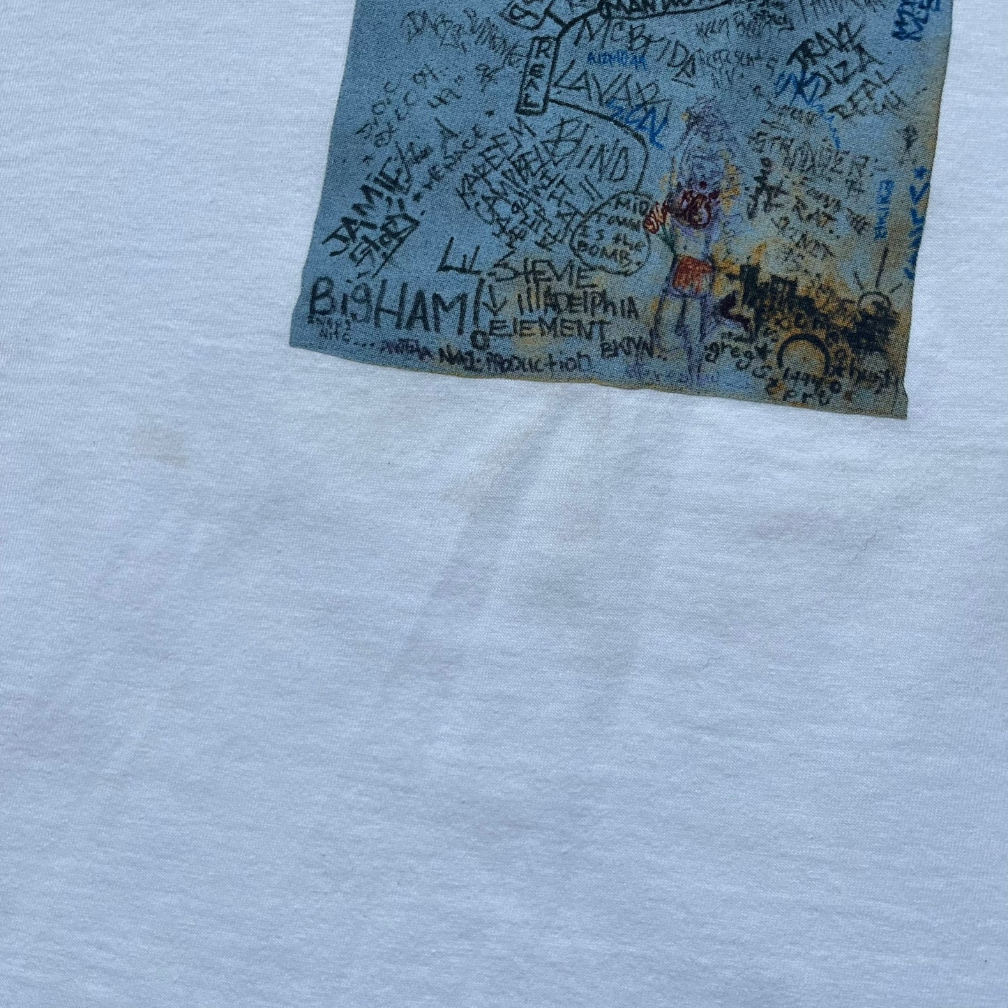 Supreme 30th Anniversary SS24 First Tee is a white T-shirt released on April 25, 2024, as part of the SS24 season. The front features a small OG Taxi Driver Supreme shirt graphic in blue with graffiti-style detailing. Below the back collar, a small gray tag displays the Supreme 30th Anniversary logo.