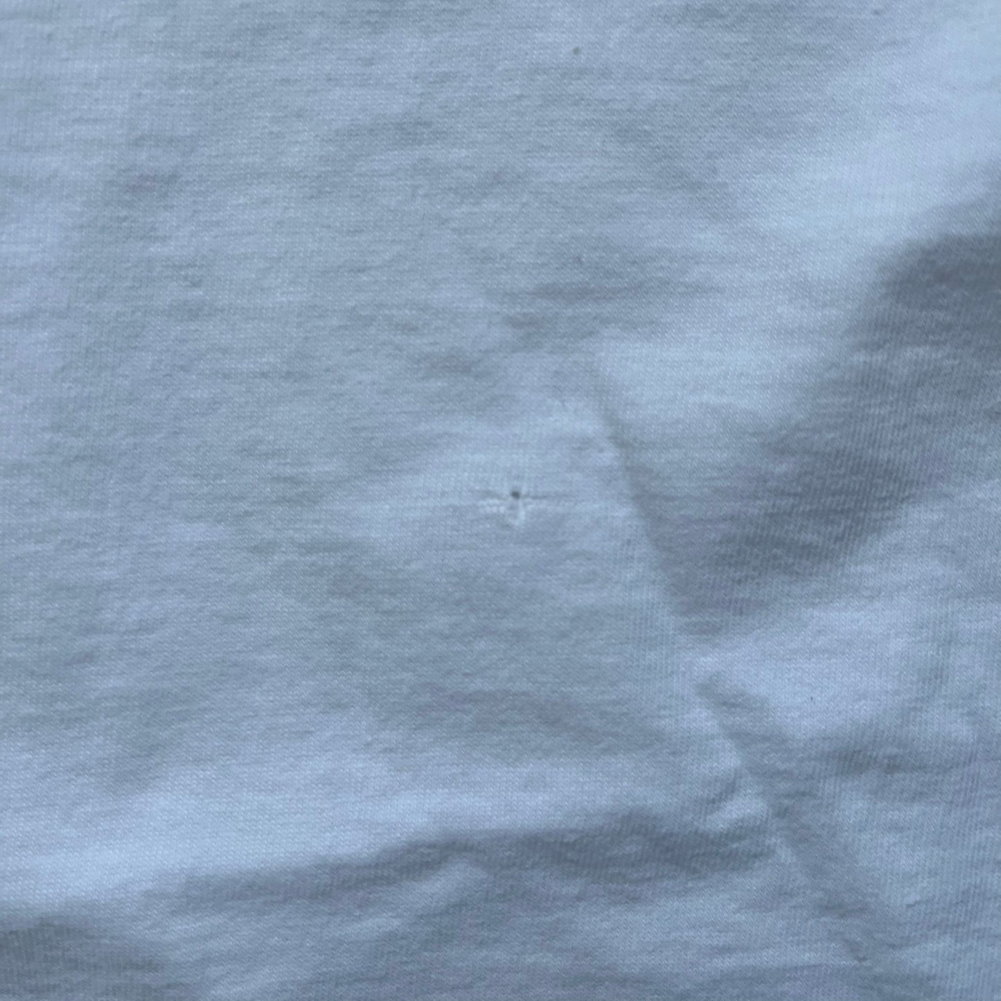 Supreme 30th Anniversary SS24 First Tee is a white T-shirt released on April 25, 2024, as part of the SS24 season. The front features a small OG Taxi Driver Supreme shirt graphic in blue with graffiti-style detailing. Below the back collar, a small gray tag displays the Supreme 30th Anniversary logo.