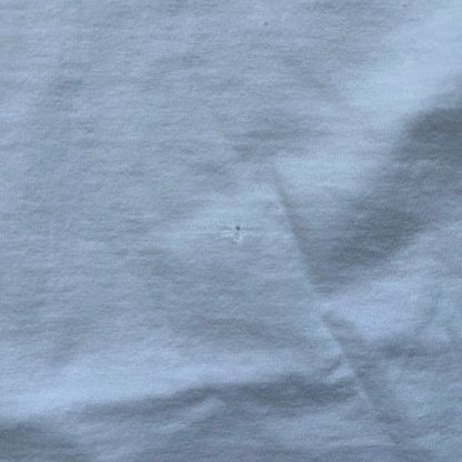 Supreme 30th Anniversary SS24 First Tee is a white T-shirt released on April 25, 2024, as part of the SS24 season. The front features a small OG Taxi Driver Supreme shirt graphic in blue with graffiti-style detailing. Below the back collar, a small gray tag displays the Supreme 30th Anniversary logo.