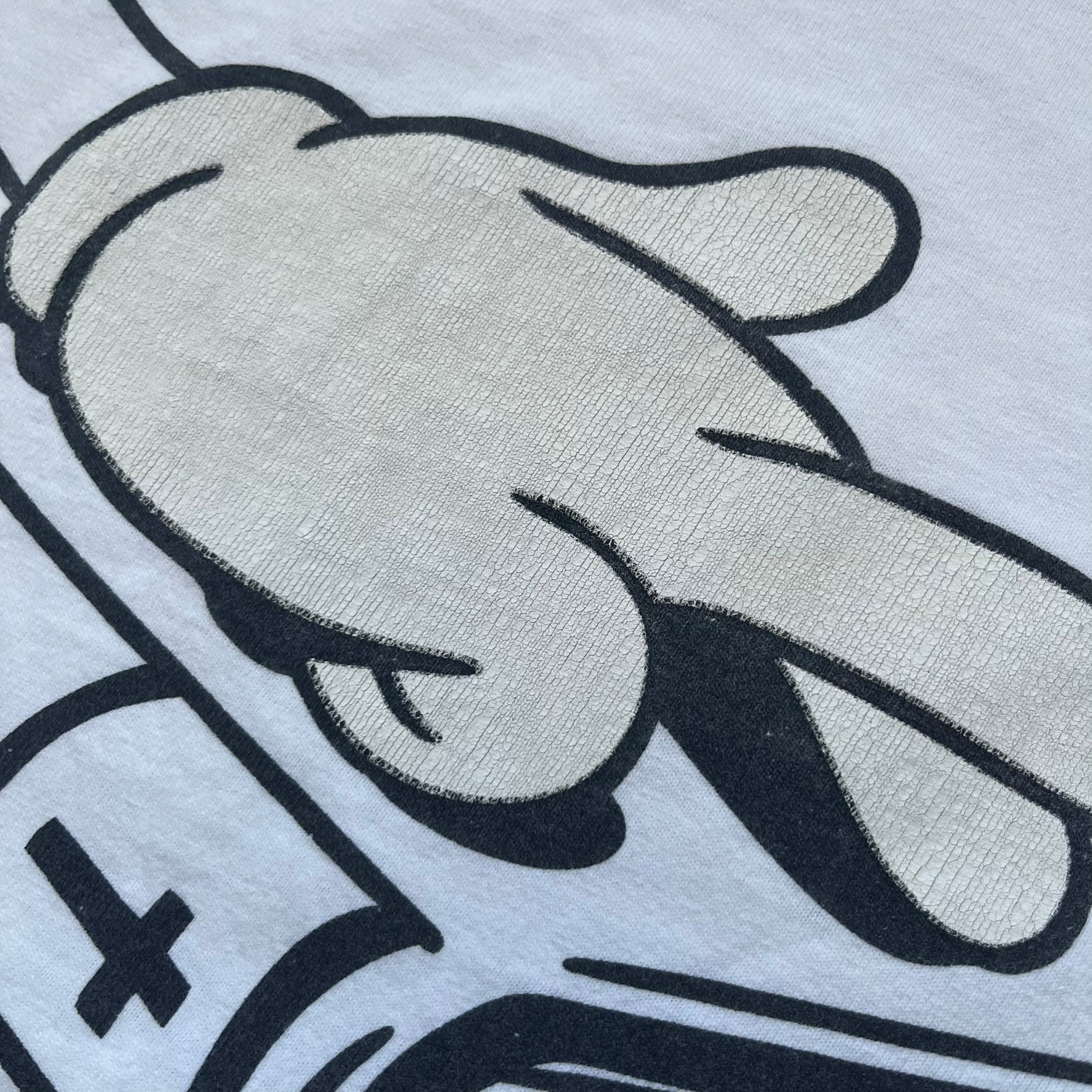 Supreme SS06 Oath White Tee is a white short-sleeve T-shirt from the Spring/Summer 2006 collection. The front features a black outline graphic of a Mickey Mouse-style hand placed on a cartoon Bible with a visible cross, with small “Supreme 2006” copyright text on the side. Super rare piece.