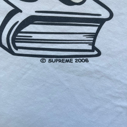 Supreme SS06 Oath White Tee is a white short-sleeve T-shirt from the Spring/Summer 2006 collection. The front features a black outline graphic of a Mickey Mouse-style hand placed on a cartoon Bible with a visible cross, with small “Supreme 2006” copyright text on the side. Super rare piece.