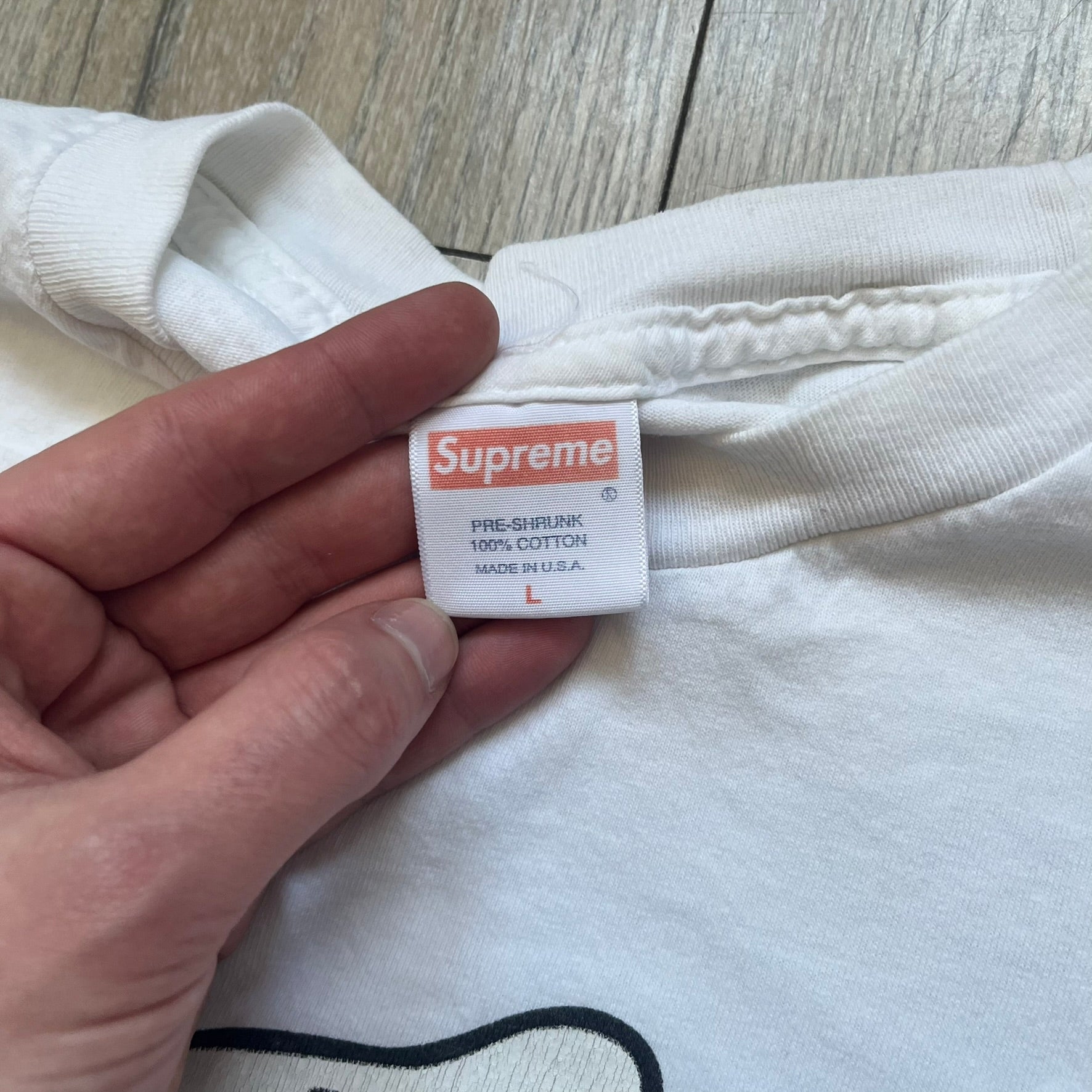 Supreme SS06 Oath White Tee is a white short-sleeve T-shirt from the Spring/Summer 2006 collection. The front features a black outline graphic of a Mickey Mouse-style hand placed on a cartoon Bible with a visible cross, with small “Supreme 2006” copyright text on the side. Super rare piece.