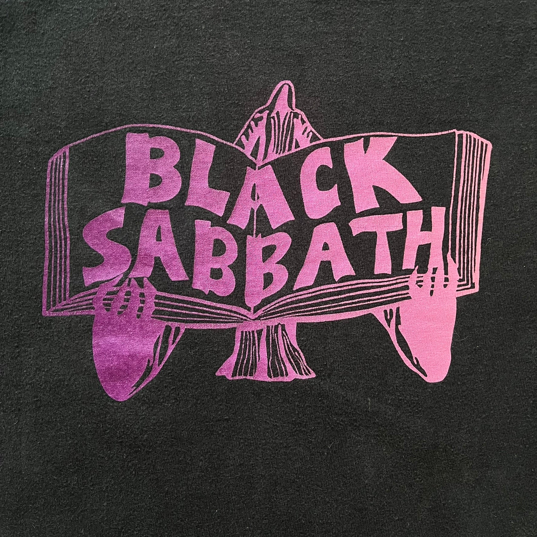From Supreme’s SS16 Black Sabbath collaboration, the Tome Tee arrives in black with striking purple graphics. The front shows the band’s Children of the Grave artwork within a book, contrasted by a gothic Supreme logo on the back. A sought-after item bridging metal iconography and Supreme’s streetwear legacy.