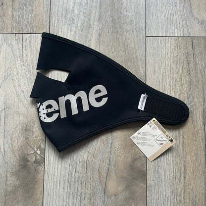 Supreme FW25 facemask produced in collaboration with GORE WINDSTOPPER® Labs, released on January 2, 2026. Constructed from water-resistant, windproof WINDSTOPPER® fabric with a fleece-bonded backing, designed for breathability and skin comfort. Features a Velcro flap closure, small front breathing perforations, nose and eye openings, a large white Supreme logo printed across the front, 3M reflective Supreme branding on the front and side, and a WINDSTOPPER® logo on the side. Finished in black.