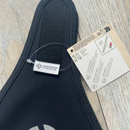 Supreme FW25 facemask produced in collaboration with GORE WINDSTOPPER® Labs, released on January 2, 2026. Constructed from water-resistant, windproof WINDSTOPPER® fabric with a fleece-bonded backing, designed for breathability and skin comfort. Features a Velcro flap closure, small front breathing perforations, nose and eye openings, a large white Supreme logo printed across the front, 3M reflective Supreme branding on the front and side, and a WINDSTOPPER® logo on the side. Finished in black.