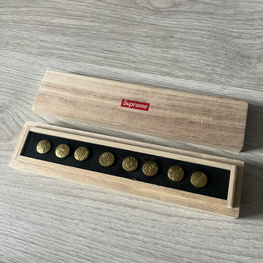 The Supreme CDW Push Pin FW24 Set, released in Week 10 (October 2024), offers eight brass-made pins with detailed debossed graphics including the classic Box Logo and “Fuck Em!” motif. Produced in Japan, this set turns simple desk essentials into collectible Supreme artifacts.