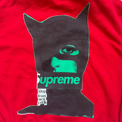 Supreme Catwoman FW23 Hooded Sweatshirt is a red pullover hoodie released on October 19, 2023. It features a drawstring hood, kangaroo pocket, and ribbed cuffs and hem. A small Supreme box logo is placed on the left chest in black.&nbsp;The back features a large Catwoman mask graphic combined with Supreme branding across the width of the design in black and green.