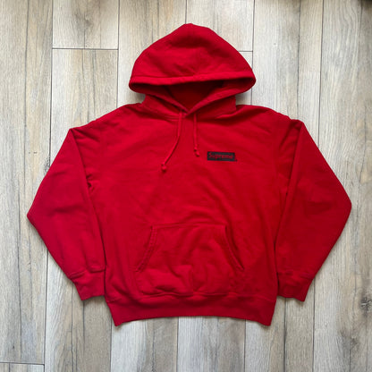 Supreme Catwoman FW23 Hooded Sweatshirt is a red pullover hoodie released on October 19, 2023. It features a drawstring hood, kangaroo pocket, and ribbed cuffs and hem. A small Supreme box logo is placed on the left chest in black.&nbsp;The back features a large Catwoman mask graphic combined with Supreme branding across the width of the design in black and green.