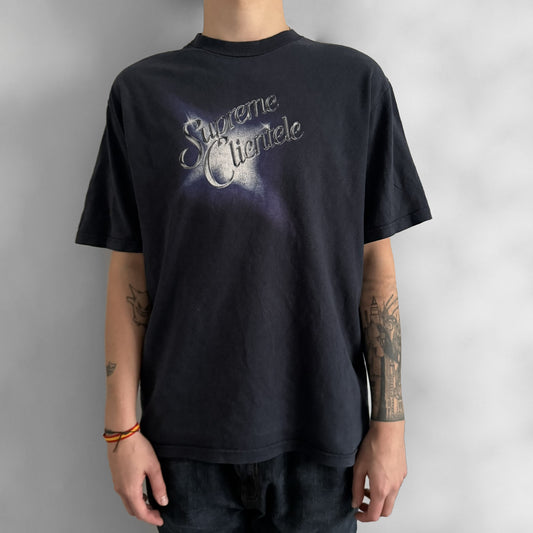 Supreme Clientele FW20 Navy Tee released in October 2020 as part of Supreme’s Fall/Winter 2020 collection. This cotton tee pays tribute to Ghostface Killah’s 2000 album Supreme Clientele, featuring the album’s iconic title graphic on the front and full tracklist on the back. A standout Supreme graphic tee that merges streetwear with hip-hop history.