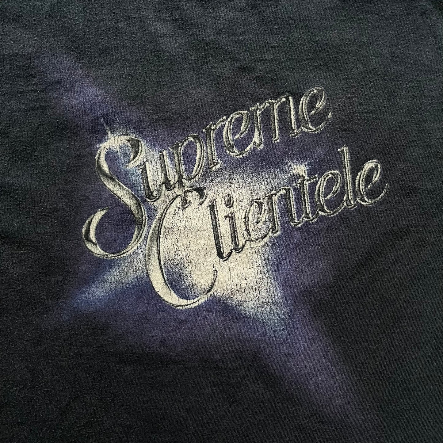 Supreme Clientele FW20 Navy Tee released in October 2020 as part of Supreme’s Fall/Winter 2020 collection. This cotton tee pays tribute to Ghostface Killah’s 2000 album Supreme Clientele, featuring the album’s iconic title graphic on the front and full tracklist on the back. A standout Supreme graphic tee that merges streetwear with hip-hop history.