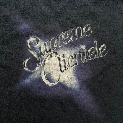 Supreme Clientele FW20 Navy Tee released in October 2020 as part of Supreme’s Fall/Winter 2020 collection. This cotton tee pays tribute to Ghostface Killah’s 2000 album Supreme Clientele, featuring the album’s iconic title graphic on the front and full tracklist on the back. A standout Supreme graphic tee that merges streetwear with hip-hop history.
