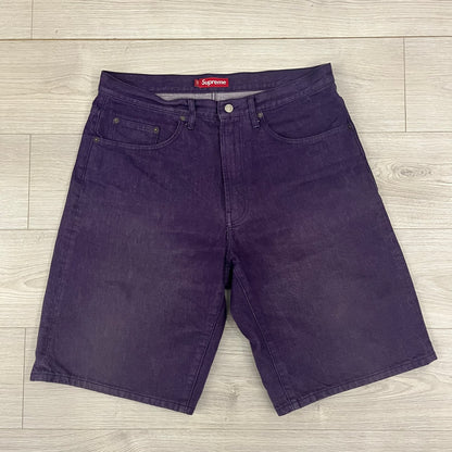 Supreme Denim Purple SS25 Baggy Shorts crafted from 13 oz. all-cotton denim in a purple hue. Features a relaxed baggy fit, classic five-pocket styling, zip fly, copper oxide rivets, and embroidered Supreme New York logo on the back pocket. Durable, stylish, and perfect for everyday streetwear.