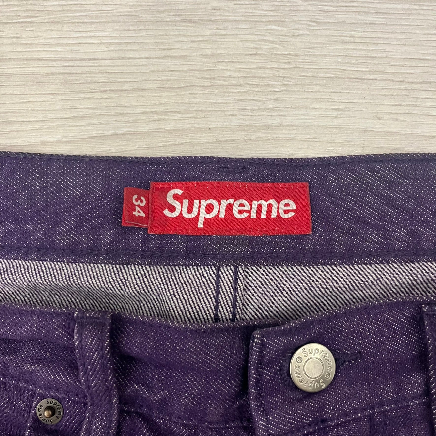 Supreme Denim Purple SS25 Baggy Shorts crafted from 13 oz. all-cotton denim in a purple hue. Features a relaxed baggy fit, classic five-pocket styling, zip fly, copper oxide rivets, and embroidered Supreme New York logo on the back pocket. Durable, stylish, and perfect for everyday streetwear.