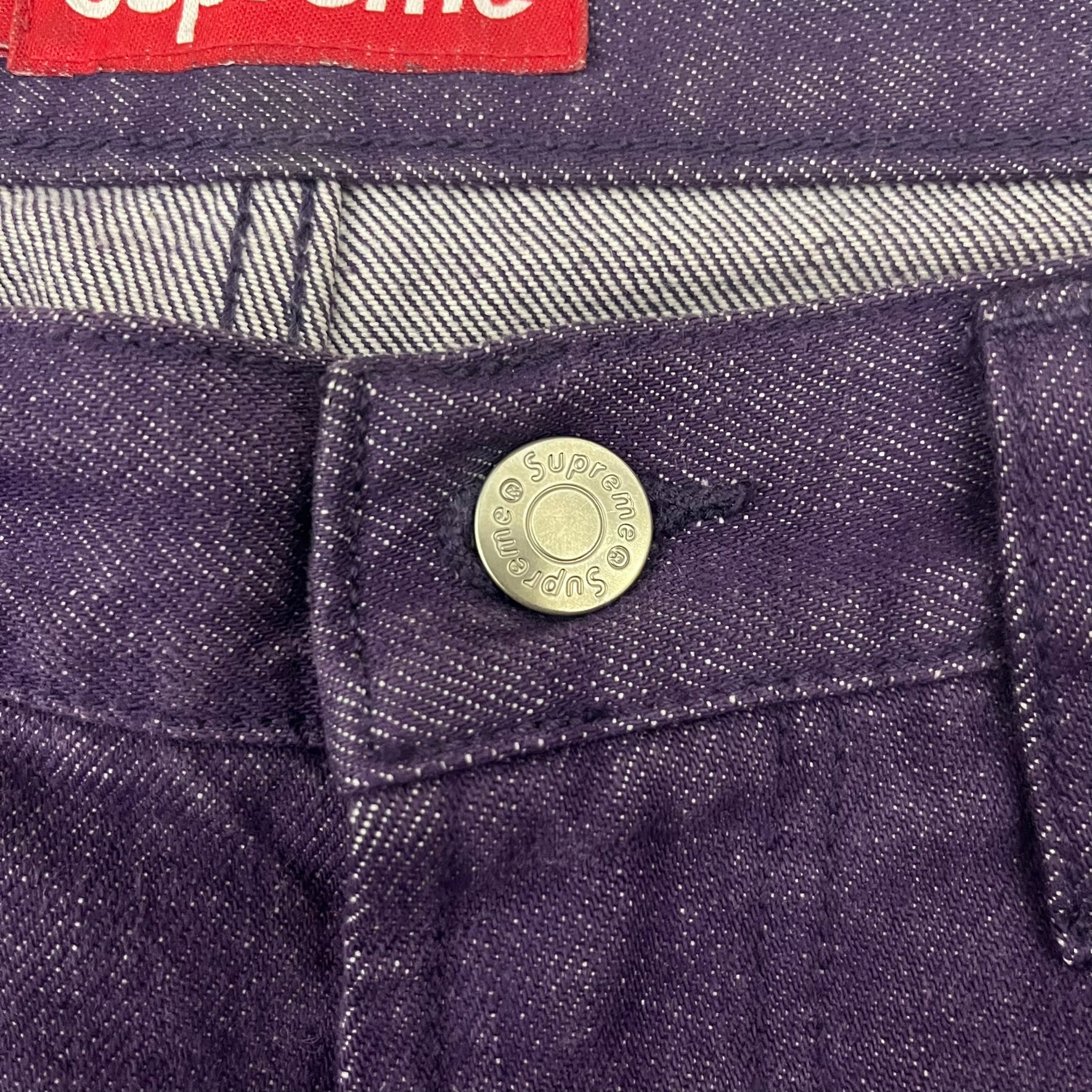 Supreme Denim Purple SS25 Baggy Shorts crafted from 13 oz. all-cotton denim in a purple hue. Features a relaxed baggy fit, classic five-pocket styling, zip fly, copper oxide rivets, and embroidered Supreme New York logo on the back pocket. Durable, stylish, and perfect for everyday streetwear.