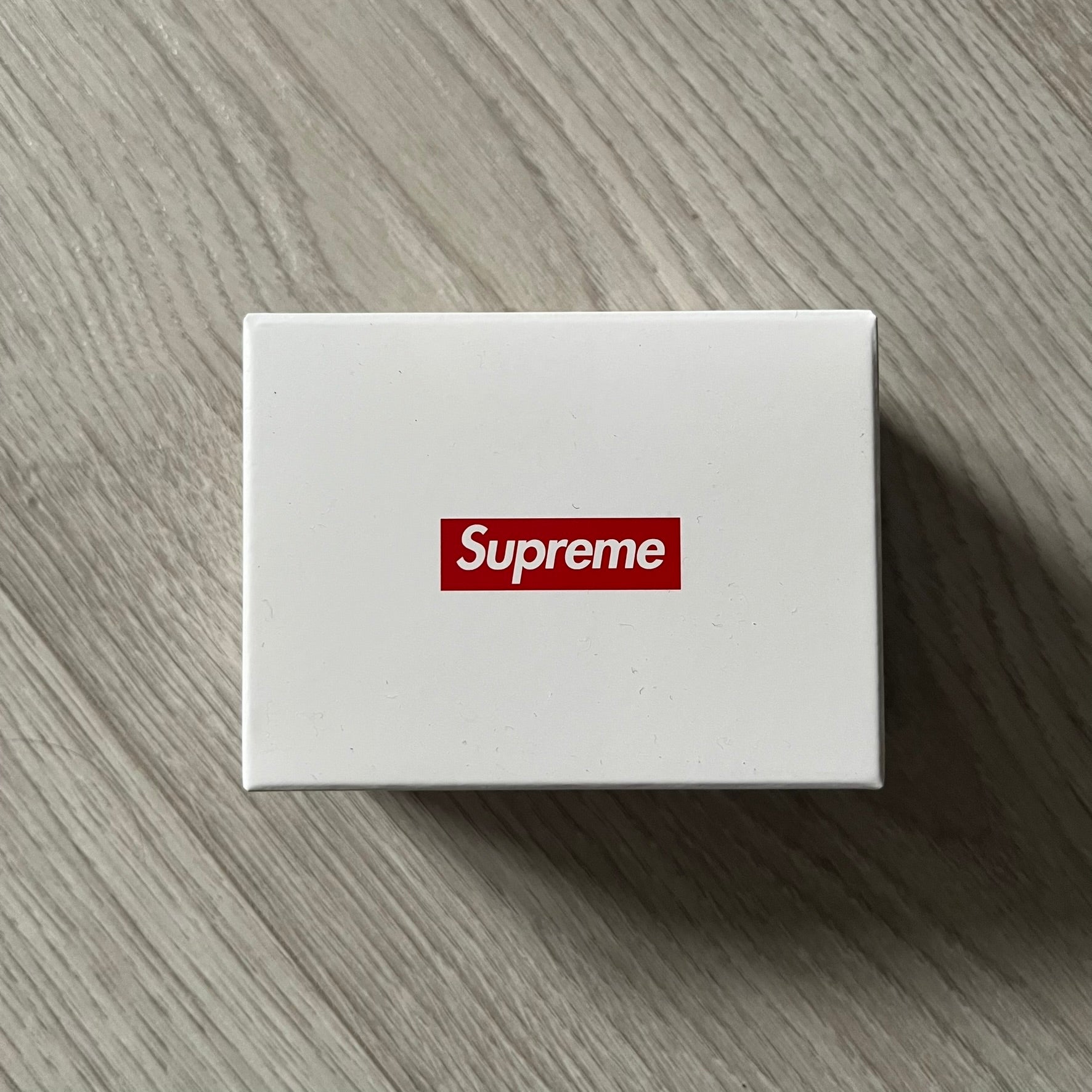 Supreme Digital Camera Keychain released for FW25 in white with a printed Supreme box logo on the front. This ultra-compact digital camera measures 1.92" x 1.14" x 1.1" and includes a 32GB TF card, USB-C cable, and built-in 1080p HD recording. When powered on, the screen displays the Supreme logo, with selectable interface colors in colors like: pink, green, or blue.