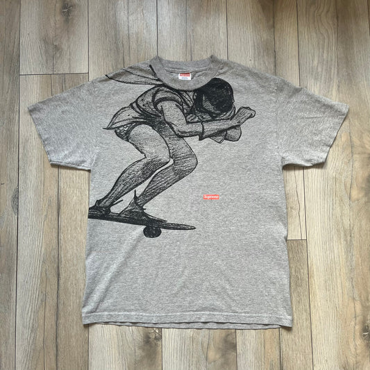 Supreme FW07 WTAPS “Live To Ride, Ride To Live” Gray Tee is a gray short-sleeve T-shirt released in Autumn/Winter 2007. The front features a black sketch of Robin on a skateboard with a small red Supreme logo beside it, while the upper back displays bold “Live To Ride, Ride To Live” text. The T-shirt was designed by Tetsu Nishiyama (WTAPS).
